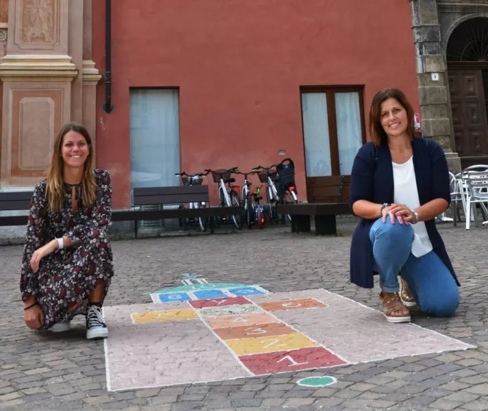 Il gioco in piazza della Rossae  le assessore alla Famiglia, Lucia Rosso, e alle Politiche giovanili, Beatrice Aimar, che seguono l’iniziativa 