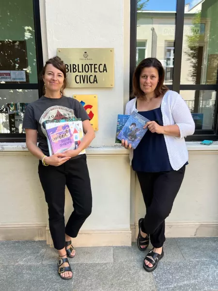 La bibliotecaria Noemi Balbo e l'assessora Lucia Rosso mostrano i nuovi libri arrivati dall'Ucraina