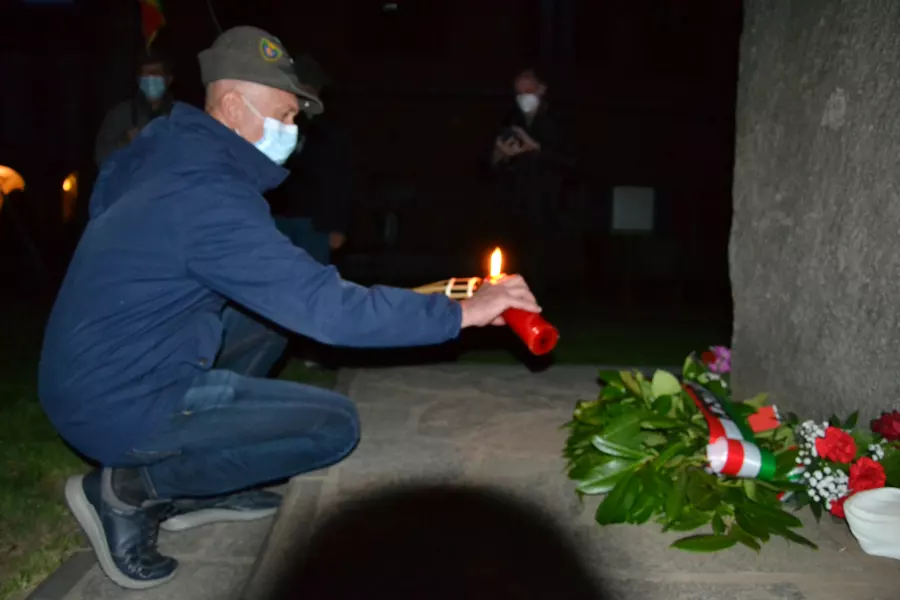 Un Alpino accende la luce della Libertà, un cero posto ai piedi del monumento alla Resistenza, dal quale i ragazzi accendono ciascuno una candela  in segno del passaggio generazionale dei valori del 25 Aprile