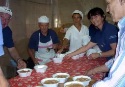 Gino e Ivana e gli altri volontari preparano i piatti con polenta e salsiccia