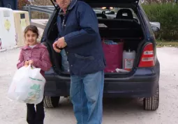 E' arrivata un'altra auto carica di rifiuti ingombranti: la bambina sta per ricevere le relative ecofigurine per la raccolta di Capitan Eco