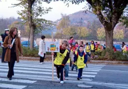 Il piedibus in arrivo dalla zona Stadio: si attraversa sulle strisce accompagnati da insegnanti, genitori e volontari della Protezione civile. Sotto la sorveglianza del vigile urbano che si trova sempre in prossimità delle scuole negli orari di entrata e uscita